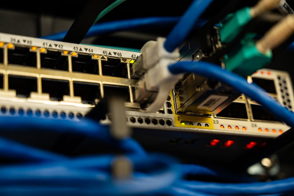 Algoritmo Redes Sociais — Close-up image of ethernet cables plugged into a network switch, showcasing IT infrastructure.